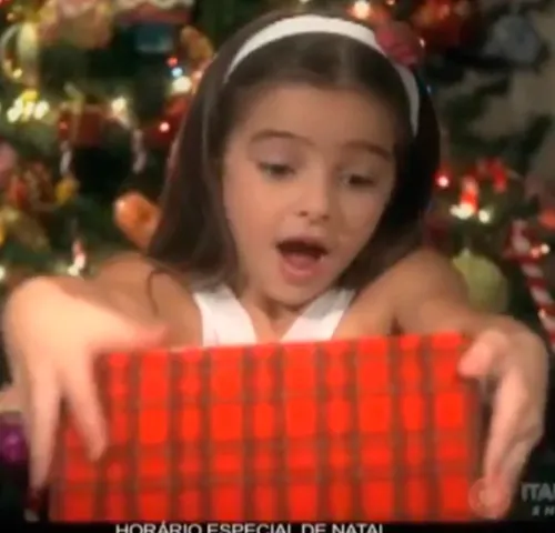 Menina abrindo um presente de Natal, cena do filme de Natal do ItaúPower Shopping